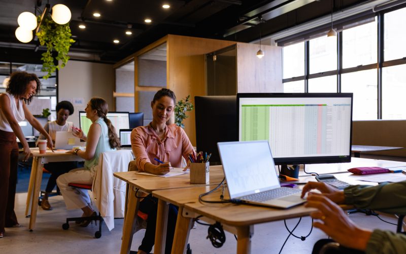 Diverse casual businesswomen working on computers at desks in office. Casual office, teamwork, business, communication and work, unaltered.